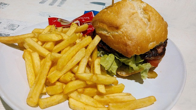 A burger and fries on a plate, illustrating a typical fast-food meal. Research suggests that diets high in such ultra-processed items promote weight gain in ways that go beyond the sheer calorie count.